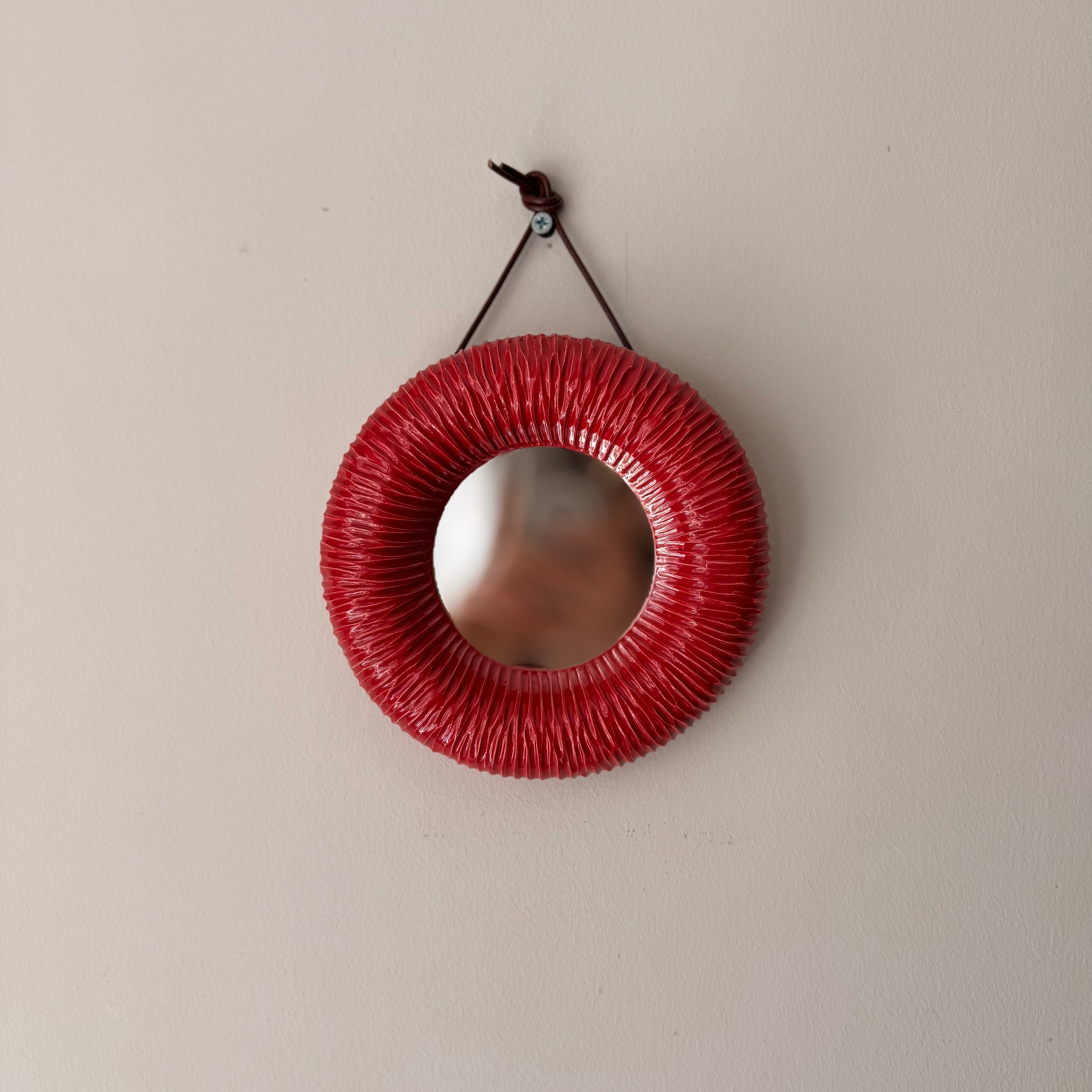 Red circular mirror with textured surface 