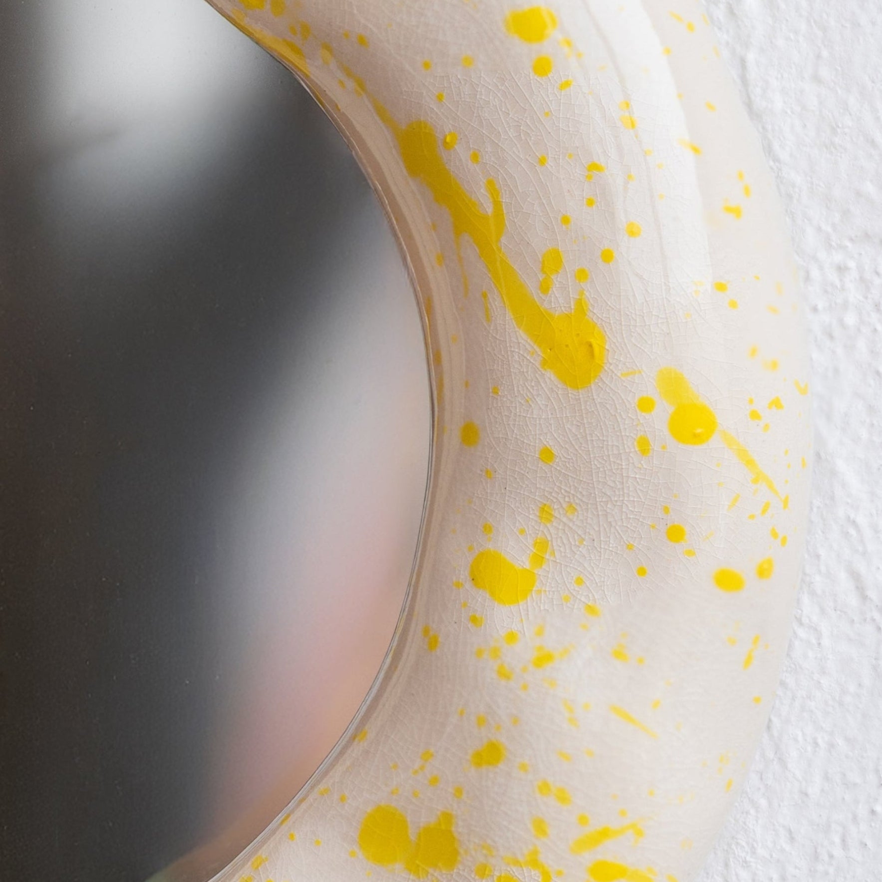 Round mirror with yellow splatter design on a white background