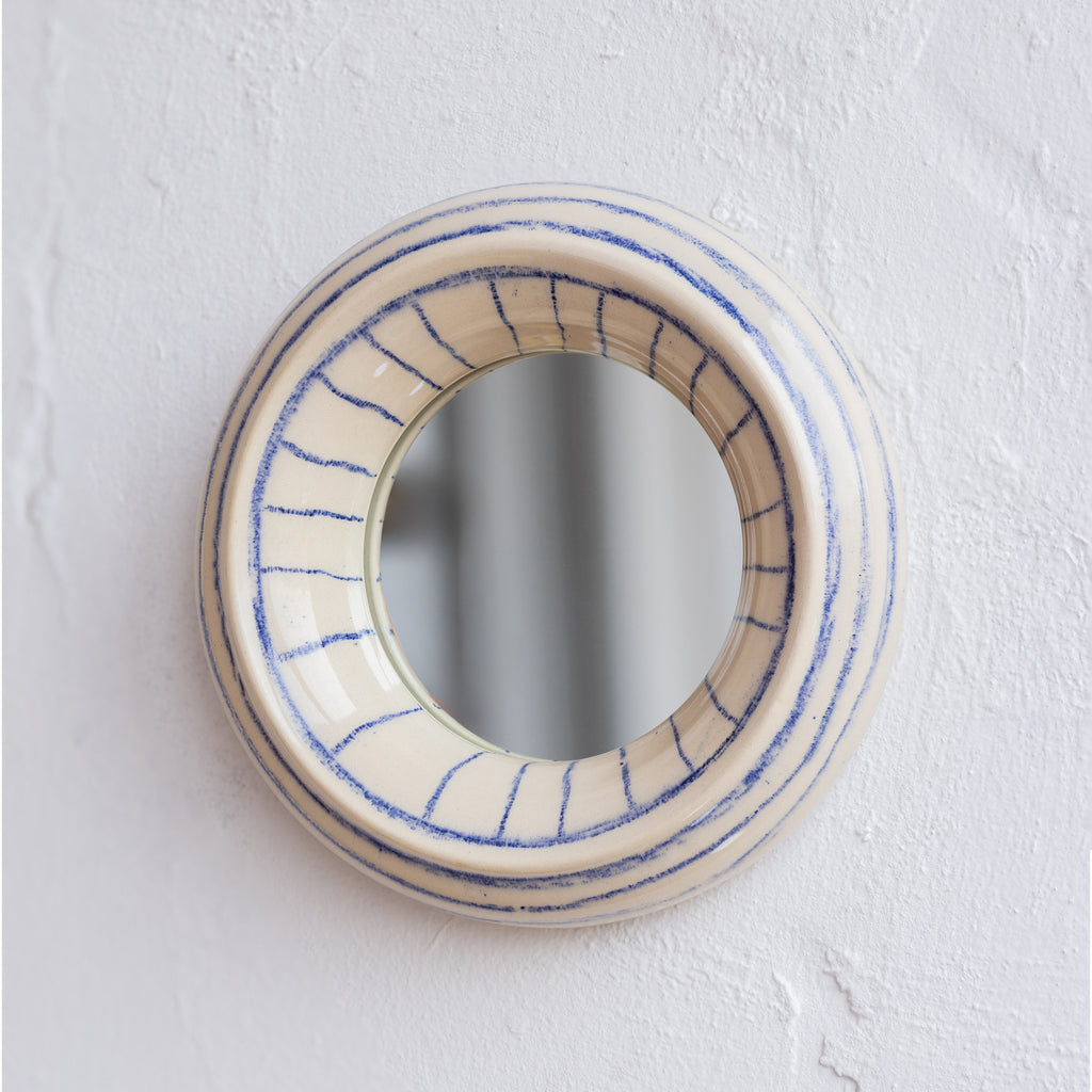 Round ceramic wall mirror with blue line design 