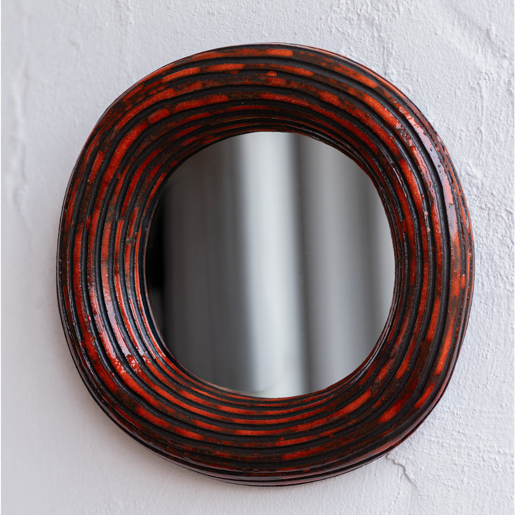 Round mirror with a decorative red and black frame 