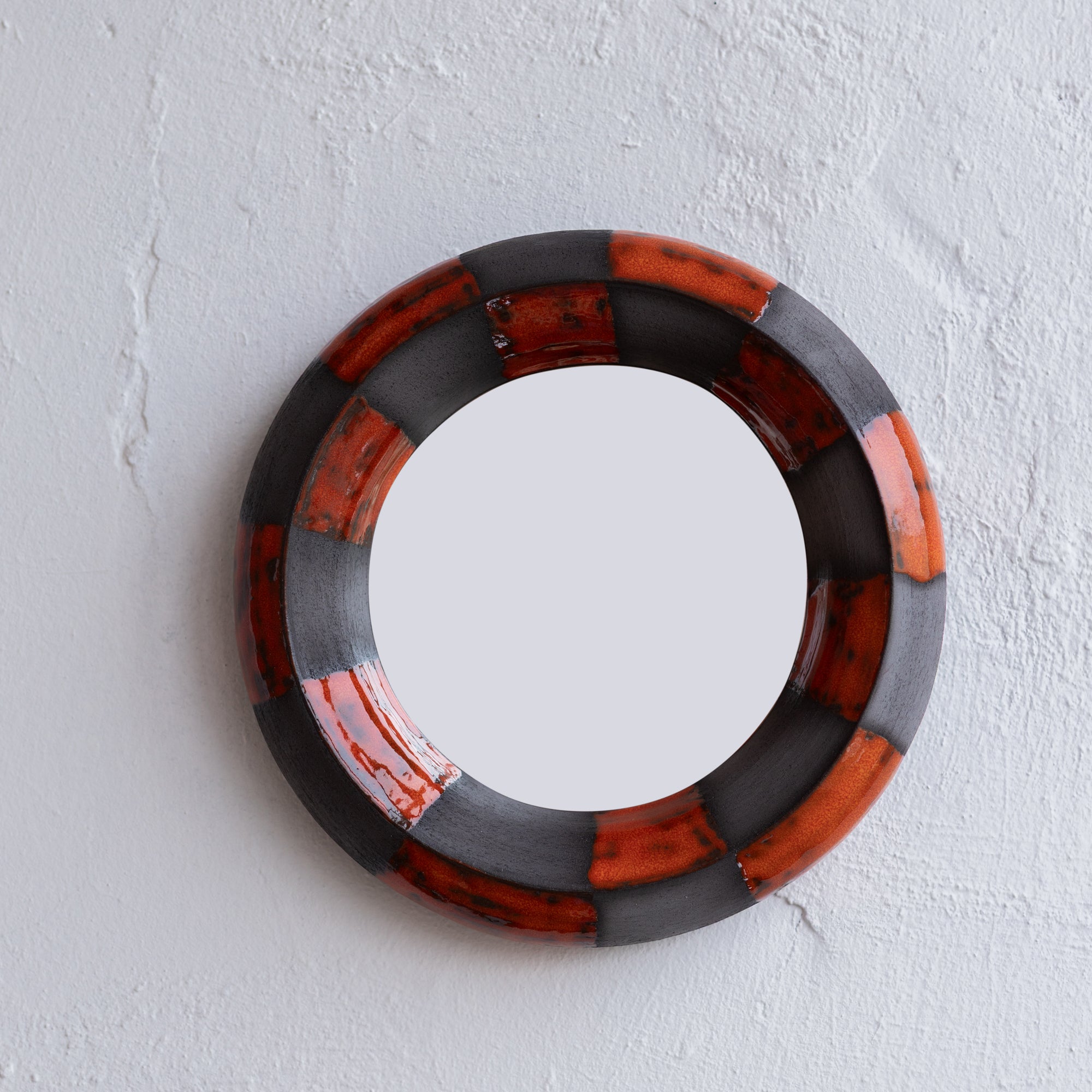 Round mirror with black and red circular design